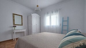 Ein Schlafzimmer mit Bett, Schrank, Schreibtisch und Spiegel.