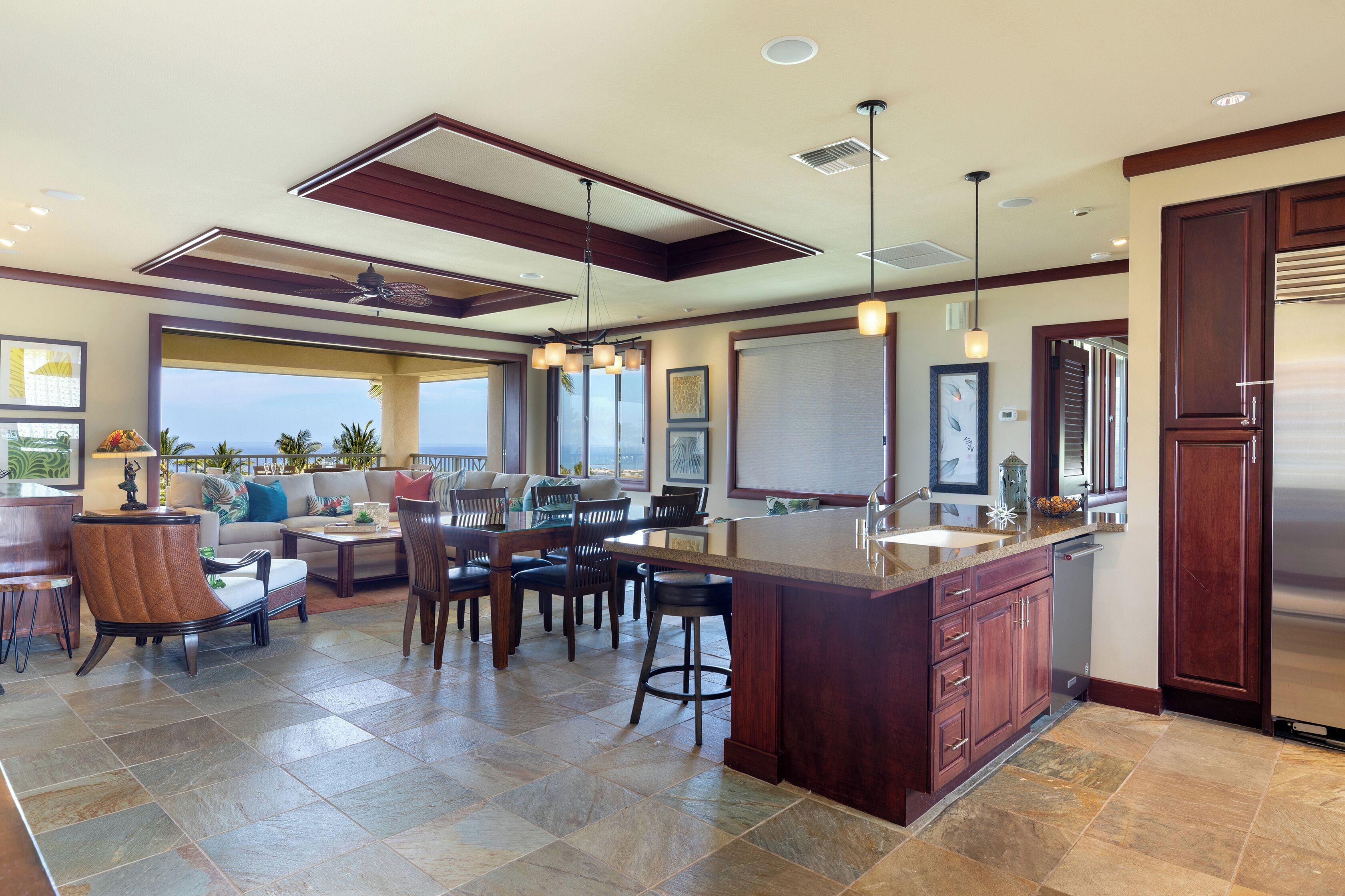 A spacious kitchen with a large island, dark wooden cabinets, and a modern ceiling design.