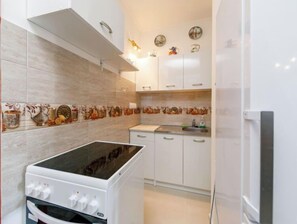 Kitchen features a modern gas stove, oven, and stainless steel sink, set against a decorative tile backsplash.