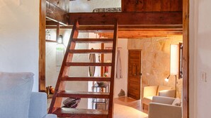 Ein Loft-Zimmer mit Holzlade, einer Couch, einem Sessel und einer Steinwand.
