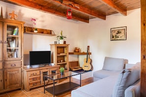 Un salon avec une télévision, des meubles en bois, une guitare et un canapé.