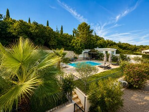 Una proprietà residenziale con piscina, una zona salotto esterna coperta e una scala che conduce al secondo piano.