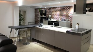 Eine moderne Küche mit Ziegelrückwand, Edelstahlgeräten und einer stilvollen Kücheninsel mit Barhocker.