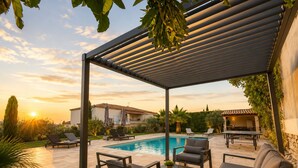 Un espace extérieur abrité comprenant une piscine, des chaises longues et une pergola.
