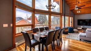 A spacious dining area with a large table and chairs, a television, and a cozy seating area with a sofa and a fireplace.