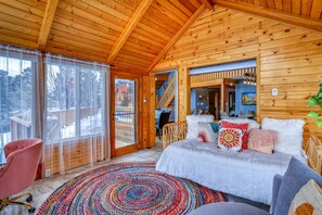 L’intérieur d’un chalet en bois chaleureux et accueillant, avec un lit, une chaise et un tapis aux couleurs vives.