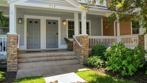Une maison à deux étages avec un porche à l’avant, des marches et une boîte aux lettres.