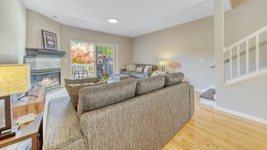 Un salon avec une cheminée, un canapé, une table basse et un escalier.