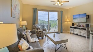 Un salon comprenant un canapé, des fauteuils, une table basse, un téléviseur et un balcon avec vue.