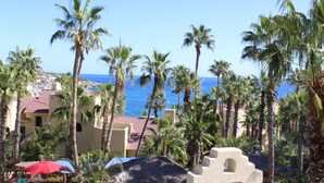 Un resort con palmeras, vista a la playa y un edificio de techo rojo.