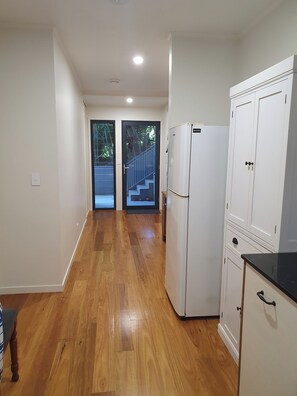 A hallway with wooden flooring, a white refrigerator, and a set of cabinets.