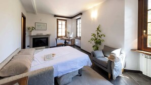 Ein Schlafzimmer mit Bett, Sofa, Kamin und Essbereich.