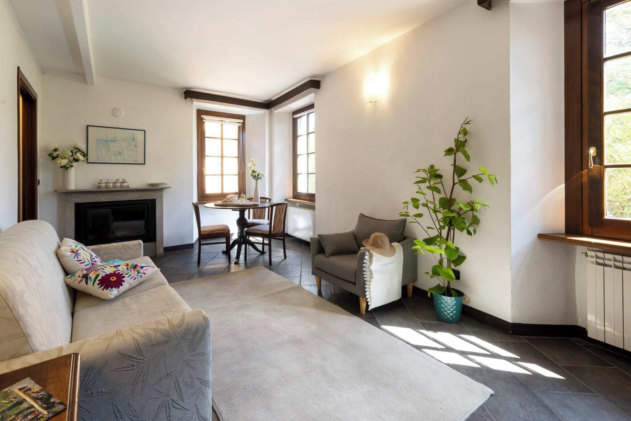 Ein Wohnzimmer mit Kamin, einem Esstisch und einer Couch mit Zierkissen.