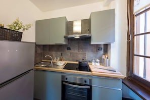 Kompakti keittiö, jossa on sisäänrakennettu uuni, pesuallas ja liesi.