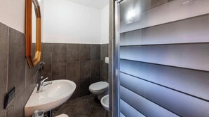 Ein Badezimmer mit einem weißen Waschbecken, einem Spiegel und einer Toilette.