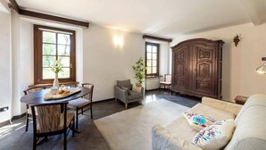 Ein Wohnzimmer mit einer Couch, einem Esstisch mit Stühlen, einem Schrank und einem Fenster mit Blick.