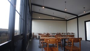 A conference room with wooden tables and chairs, large windows, and pendant lighting. - Djuragan Kamar Slipi (Jakarta)