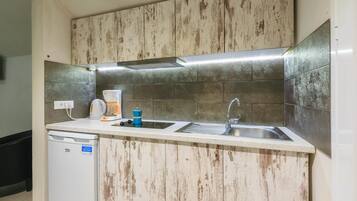 A kitchen with wooden cabinets, a dishwasher, a sink, and a countertop with a kettle and coffee maker.