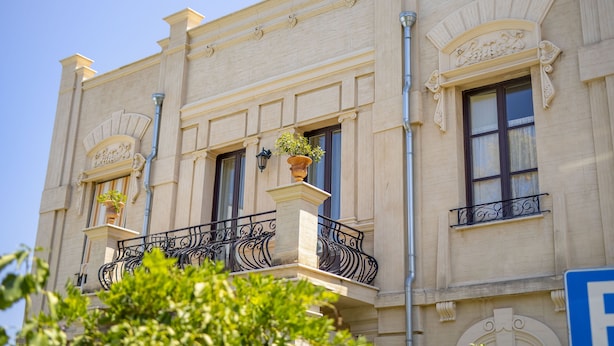 Un bâtiment à l’architecture classique, caractérisé par des balcons richement décorés, de grandes fenêtres et des moulures ornementales.