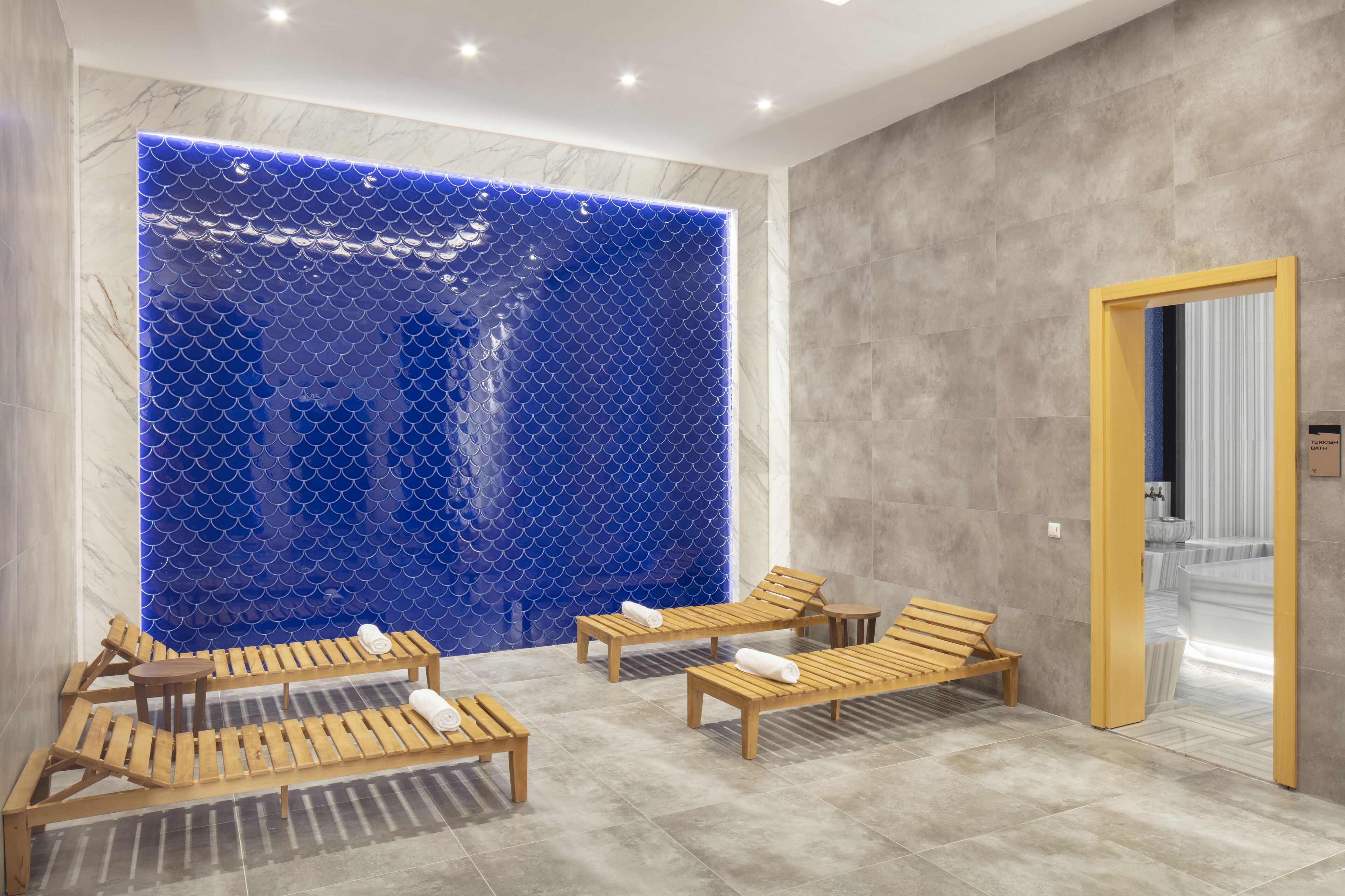 Un espace de détente avec des chaises longues en bois et un mur bleu à texture.