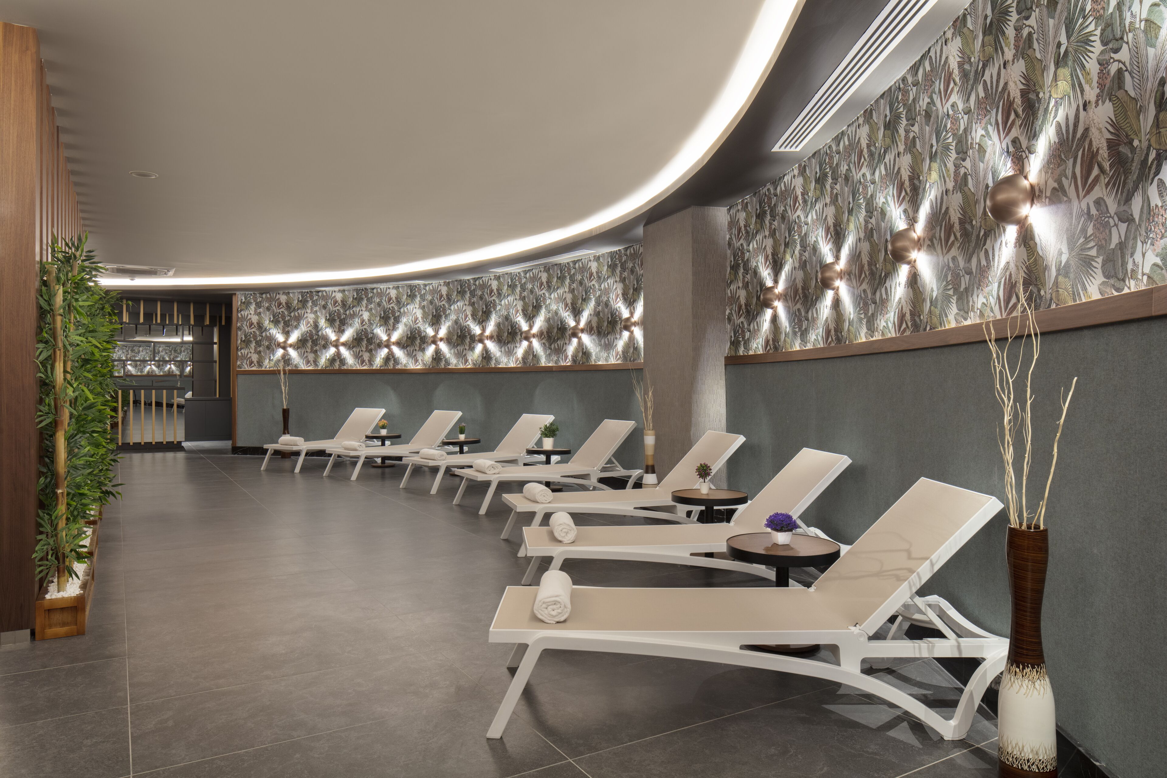 A modern spa area with lounge chairs, a decorative wall, and a plant arrangement.