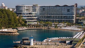 Ein Hotel am Wasser mit mehreren Balkonen, einem Poolbereich und einer Anlegestelle.