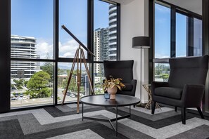 A modern room with large windows, a round table, two black chairs, a floor lamp, and a tripod. - Koko Broadbeach (Broadbeach)