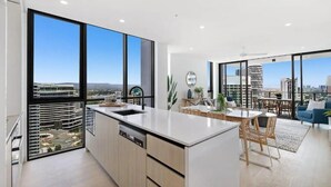 A modern kitchen with large windows, a dining area with a view, and a living space with a sofa and a coffee table. - Koko Broadbeach (Broadbeach)