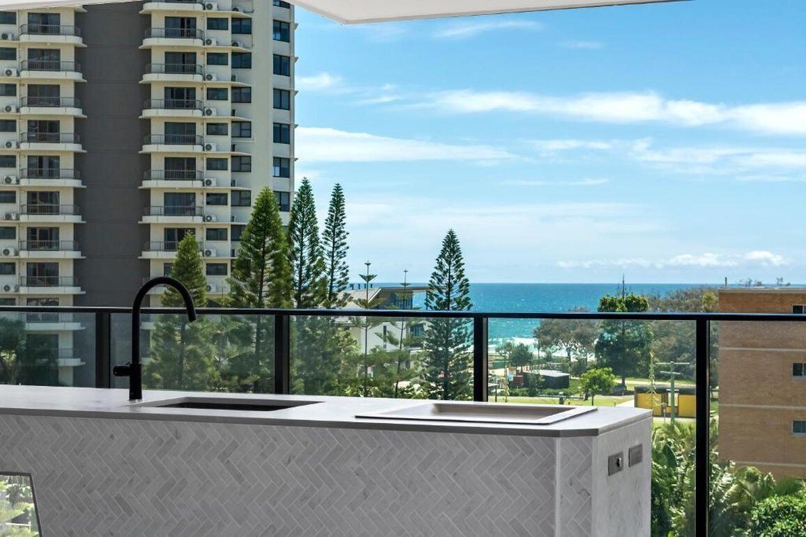 Un balcon avec un évier et une vue sur l’océan et les bâtiments.