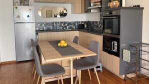 Una cocina moderna con una mesa de comedor, sillas, un refrigerador, horno y microondas.