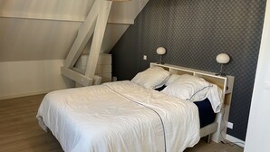A bedroom with a bed, bedside lamps, a nightstand, and a wall-mounted shelf. - Villa (Talloires-Montmin)