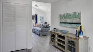 Una sala moderna con un sofá gris, una consola de madera y un cuadro en la pared.