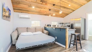 Ein Schlafzimmer mit Bett, einer Küchenzeile und einer Holzbalkendecke.