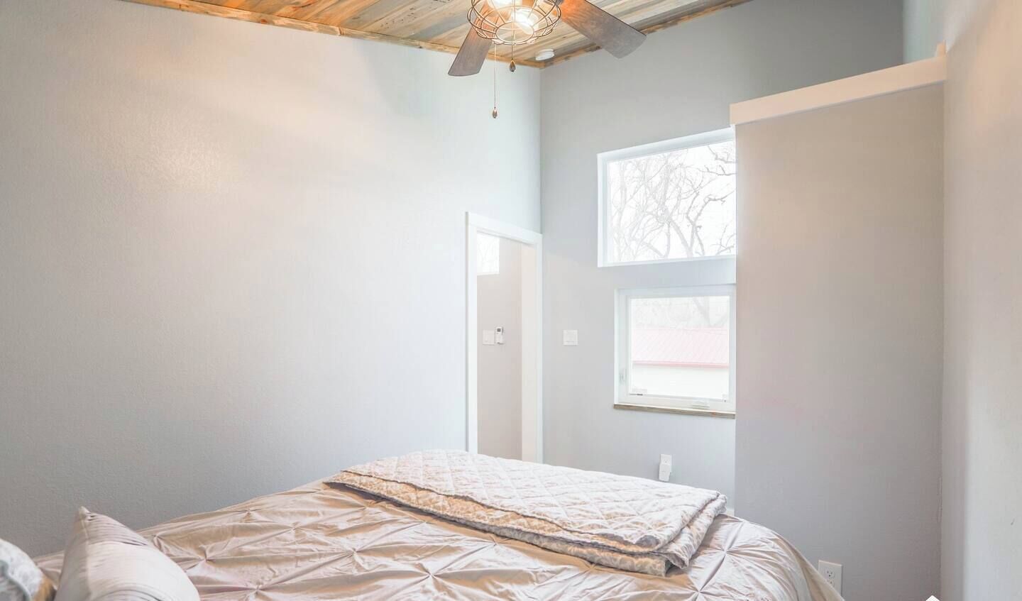 A bedroom with a bed, a ceiling fan, and a window.