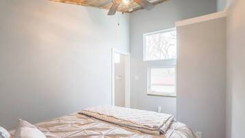 A bedroom with a bed, a ceiling fan, and a window.
