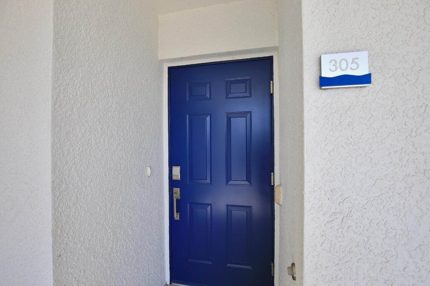 A blue door with a number sign above it indicating room number 305.