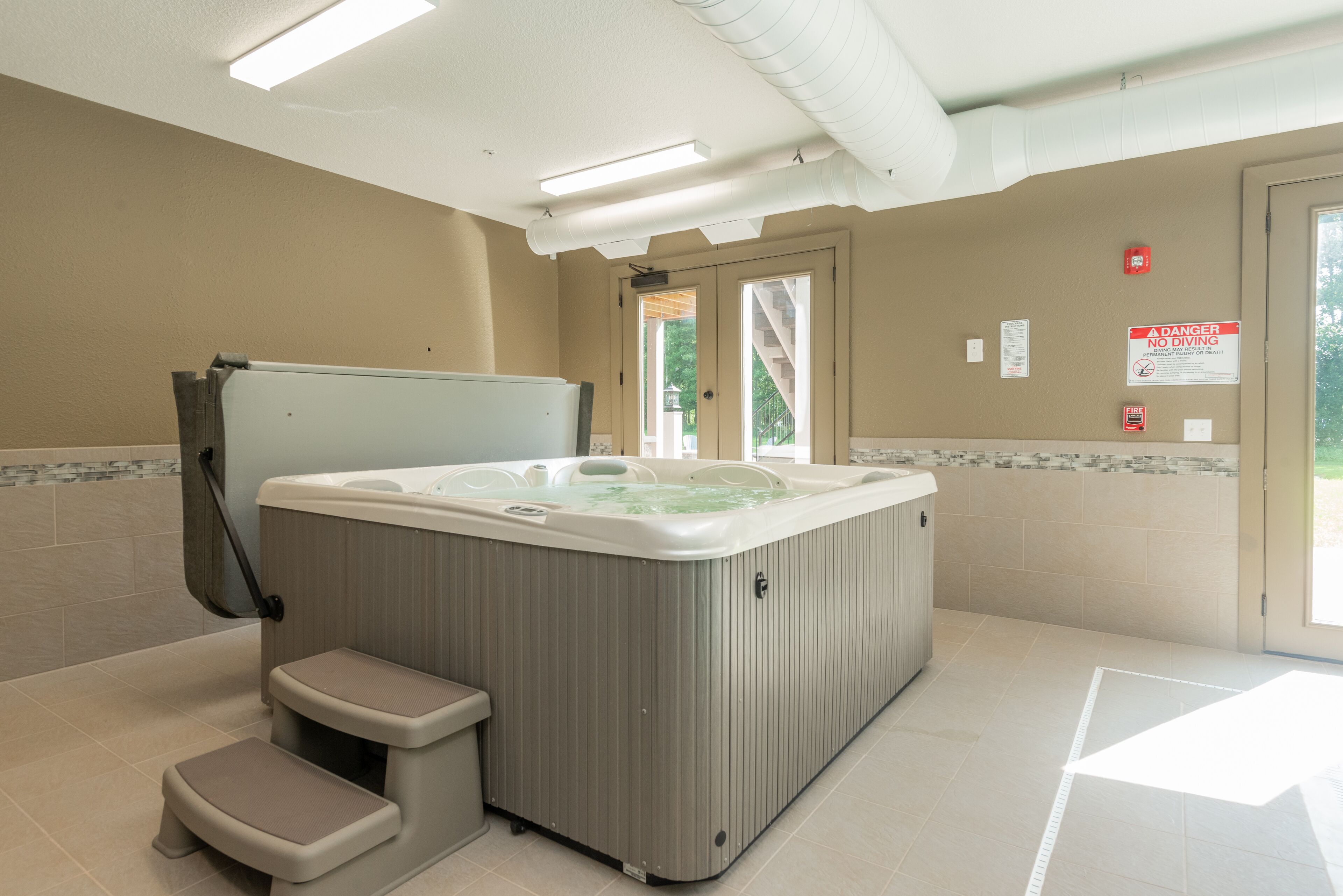 Een bubbelbad in een ruimte met beige wanden, een raam en een deur.