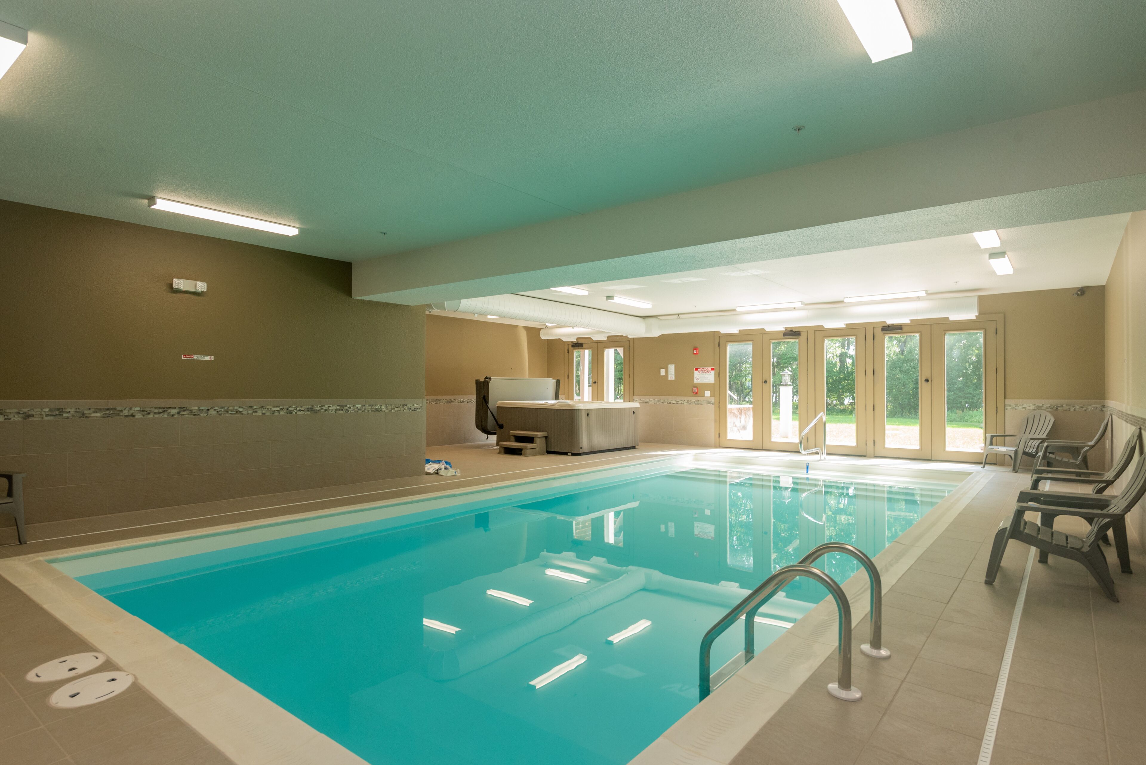 An indoor swimming pool with clear water, a lifeguard chair, and a sauna area.