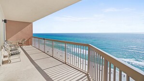 A balcony with a view of the ocean, a table with chairs, and a railing. - Sunrise Beach 1611 Gulf Front Corner Condo Sleeps 10 (Panama City Beach)