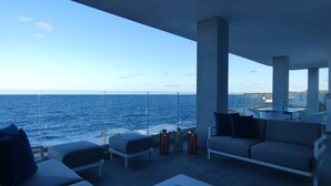 Ein moderner Außenbereich mit Meerblick, ausgestattet mit Sofas, einem Tisch und Dekoration.