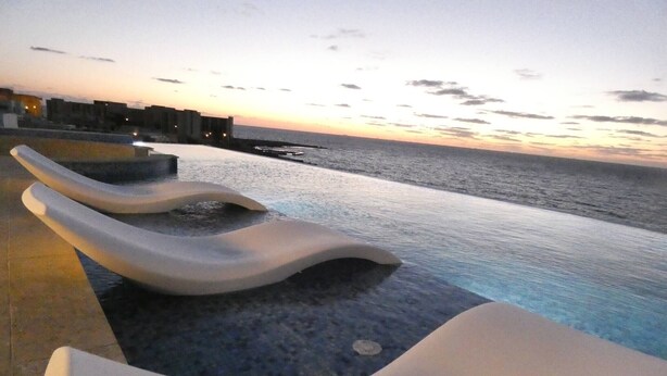 Ein Poolbereich mit Blick auf den Ozean bei Sonnenuntergang.