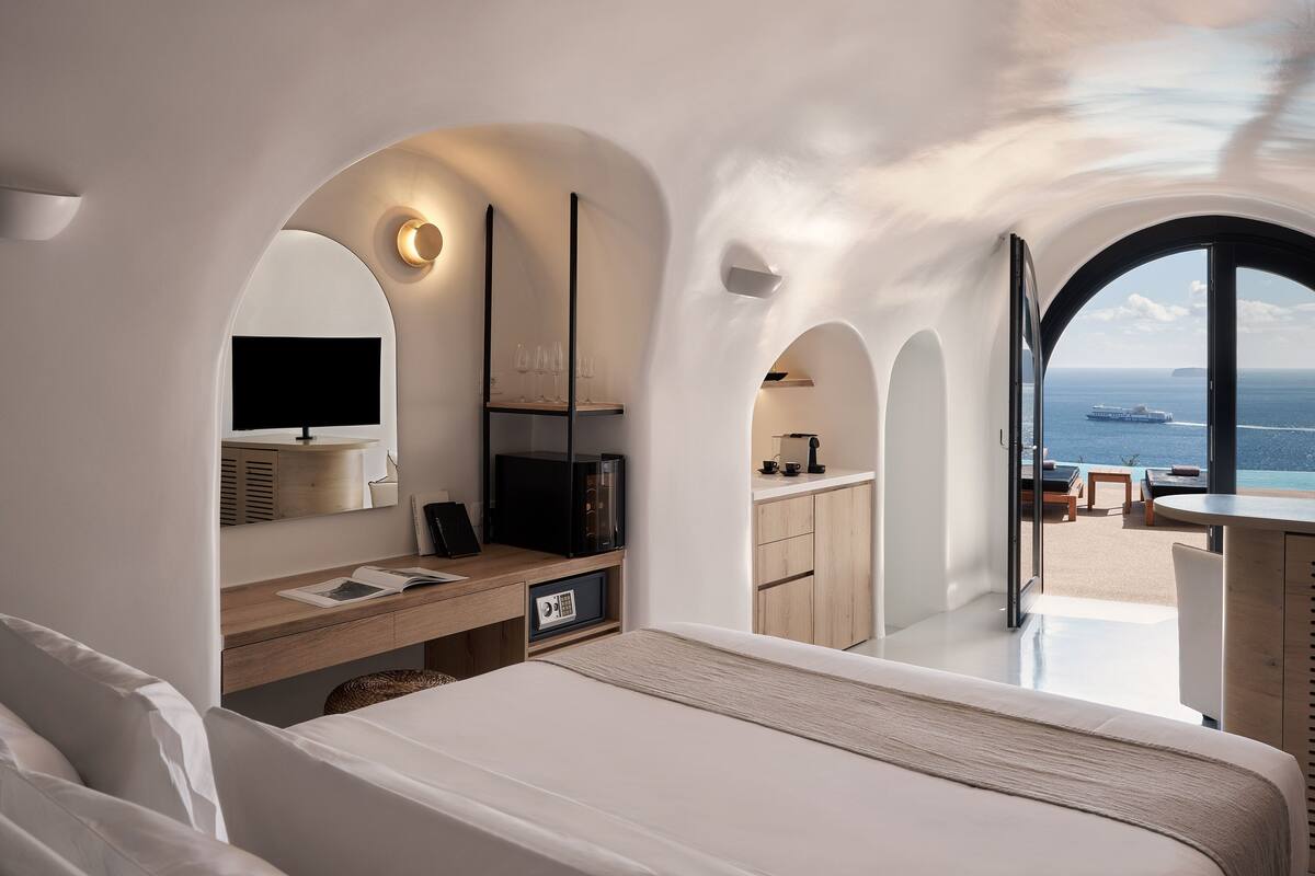 Ein modernes Schlafzimmer mit einem großen Bett, einem Schreibtisch und Blick auf das Meer.