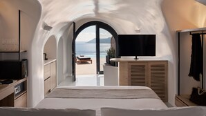 Un dormitorio con una cama grande, televisión y vista al mar.