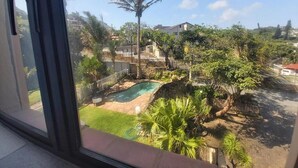 A view of a residential area with a swimming pool, palm trees, and houses in the background. - Crayfish Inn no.5 (Margate)