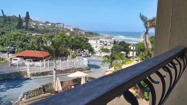 A balcony with a view of a coastal area, including a beach, a white fence, and buildings in the background. - Crayfish Inn no.5 (Margate)