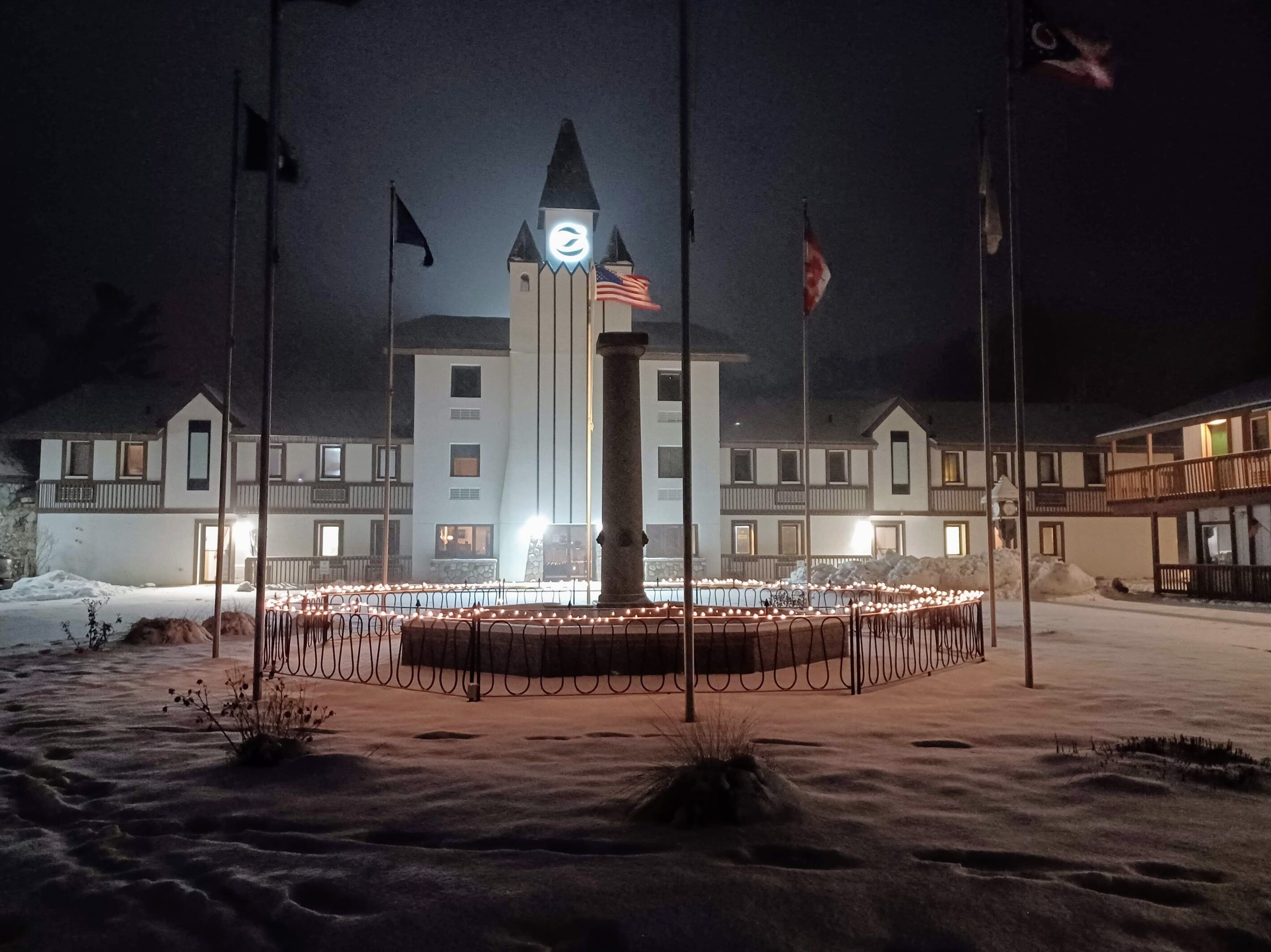 A hotel with a central tower, multiple flags, and a snow-covered ground.