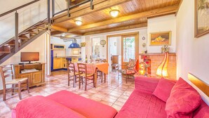 Een ruime woonkamer met een trap, houten meubels en een keuken op de achtergrond.