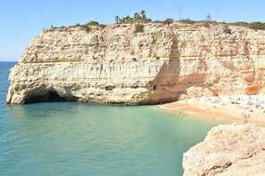 Une falaise côtière avec une plage et des eaux cristallines.