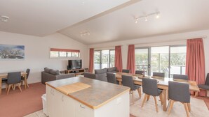 A spacious living area with a dining table, sofas, and a TV. - Reedy's Run - 11 Reedy's Cutting (Jindabyne)