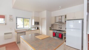 A modern kitchen with a central island, stainless steel appliances, and a window providing natural light. - Reedy's Run - 11 Reedy's Cutting (Jindabyne)